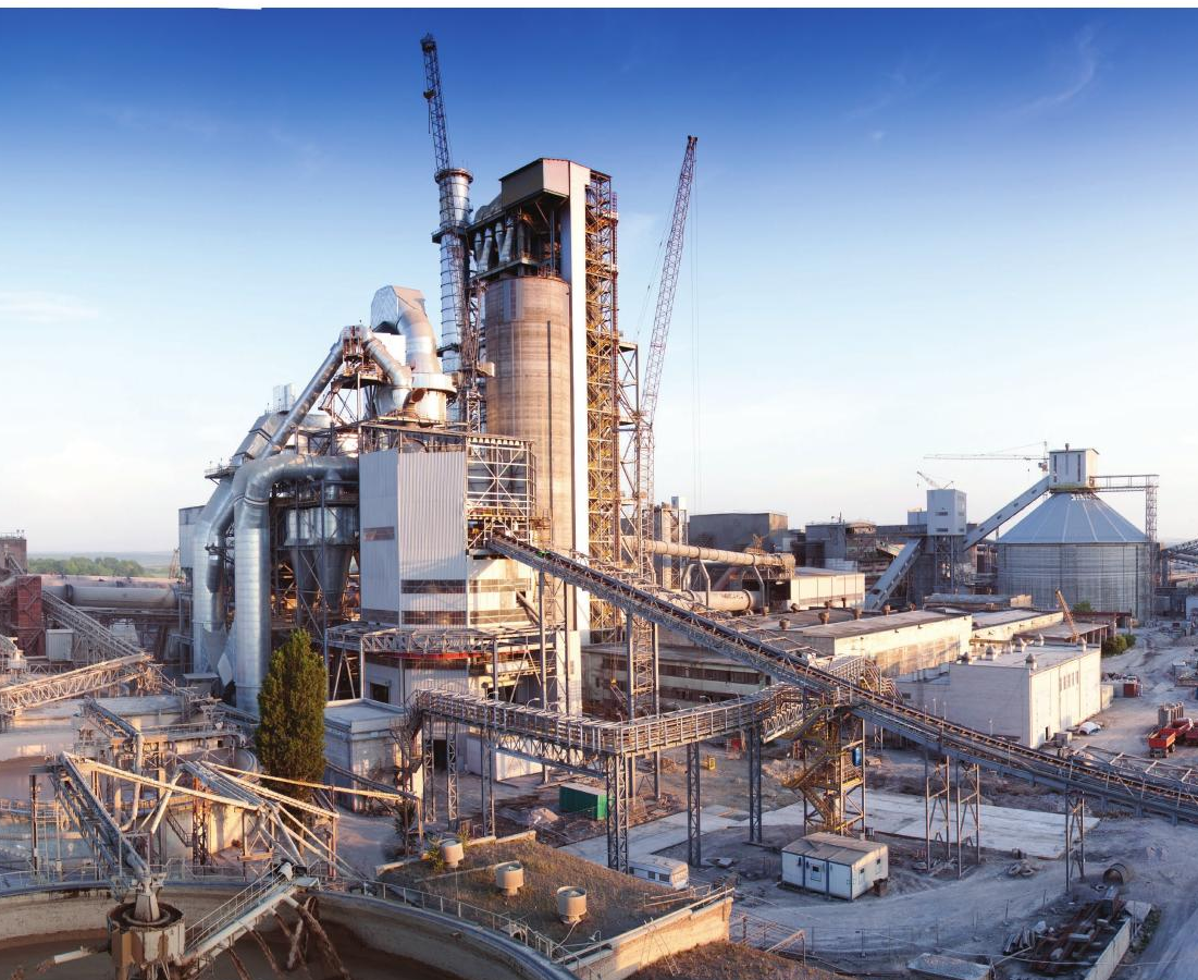 Cement plant with kiln tower, cranes and conveyor lines in the early morning light
